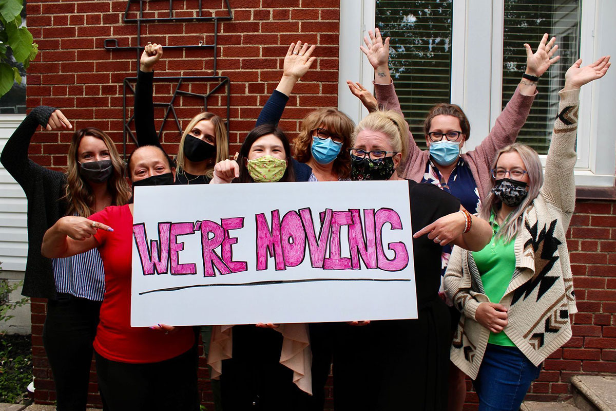 Women cheering we're moving sign